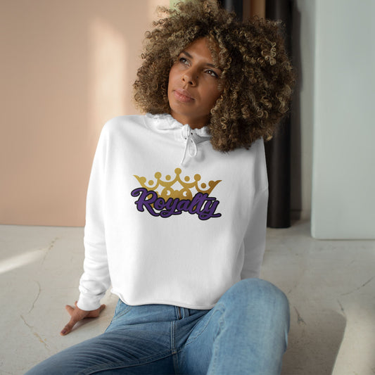 Woman wearing a white hoodie with 'Royalty' and a crown design, sitting indoors.