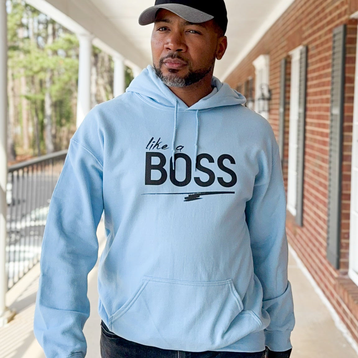 Man wearing a light blue hoodie with 'like a BOSS' text in an outdoor setting.